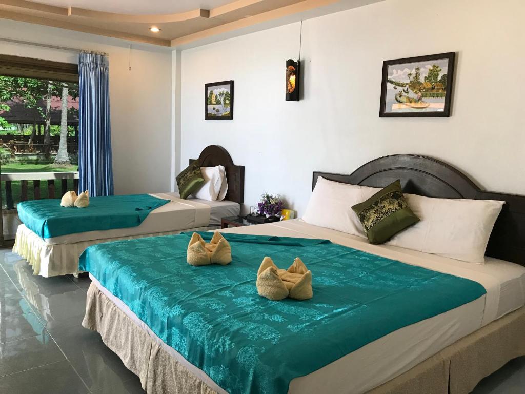 ジュム島にあるSeason Bungalowの青いシーツが敷かれたホテルの部屋にベッドが2つ