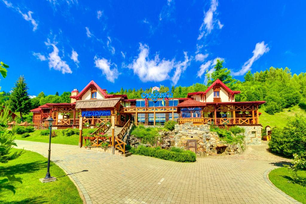a large wooden house with a stone driveway at Slovyanka Hotel in Slavske