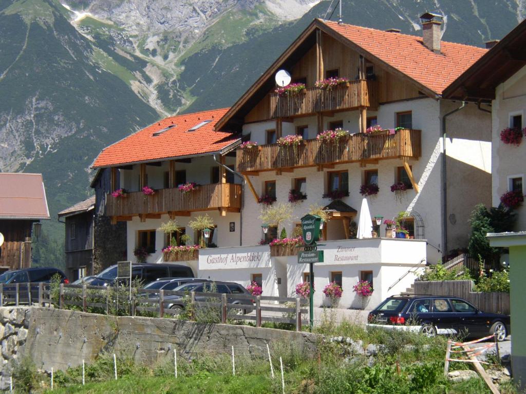 ein Gebäude mit Blumen auf den Balkonen in der Unterkunft Gasthof Alpenblick in Tobadill