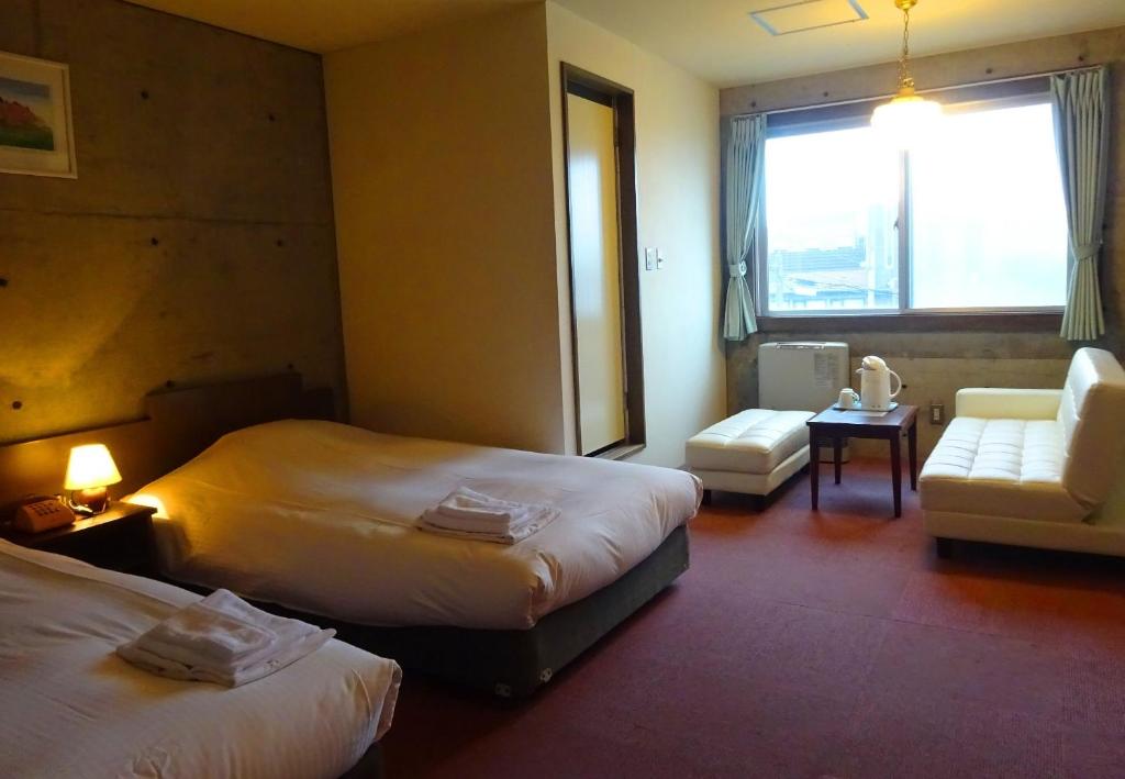 
a hotel room with two beds and a television at Hakodate Motomachi Hotel in Hakodate
