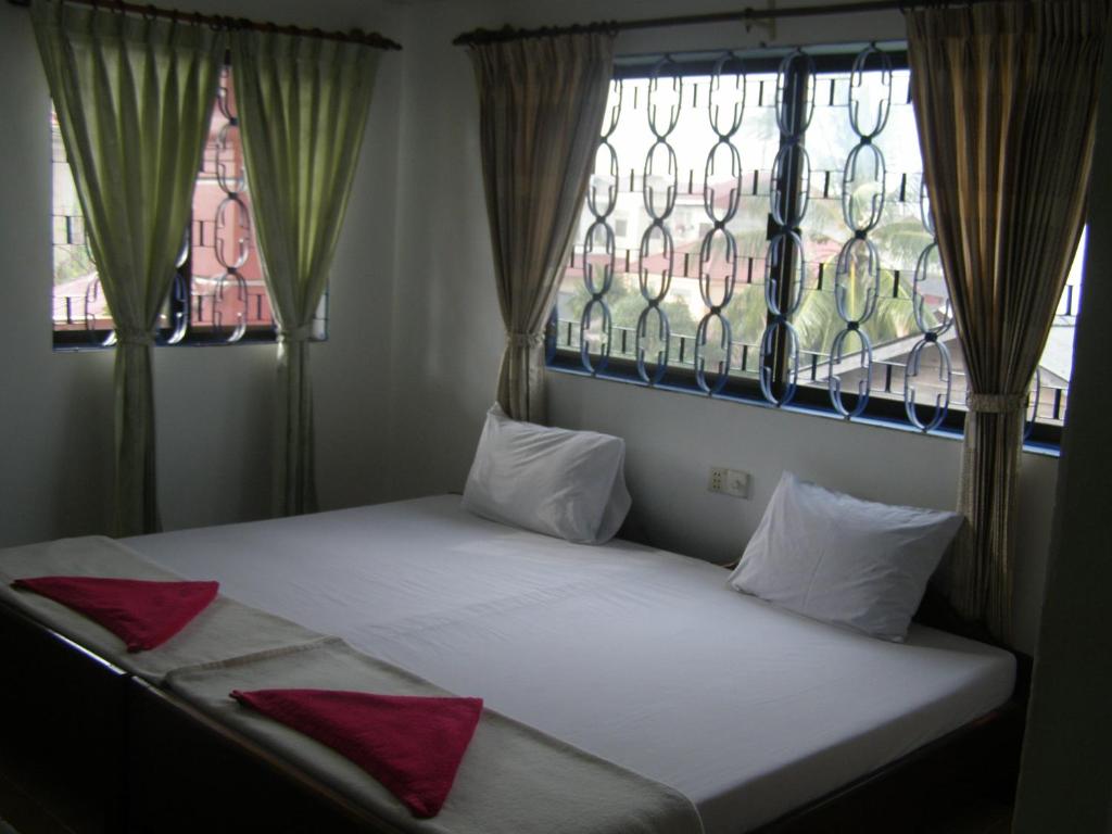 a bed with red pillows in a room with two windows at Bun Kao Guesthouse in Siem Reap
