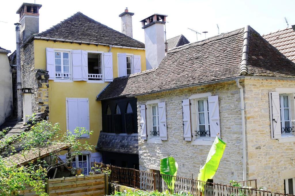 una antigua casa de piedra con ventanas blancas y una valla en Les appartements du Relais du Jacquet, en Navarrenx
