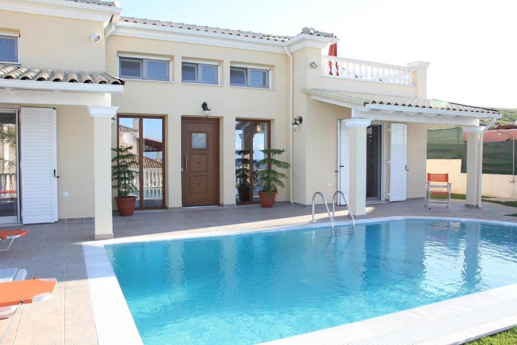 a villa with a swimming pool in front of a house at Villa de la Mer in Agios Stefanos