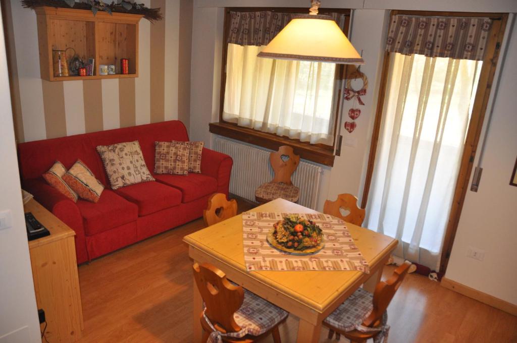 ガッリオにあるAppartamento Altopiano Di Asiagoのリビングルーム(赤いソファ、テーブル付)