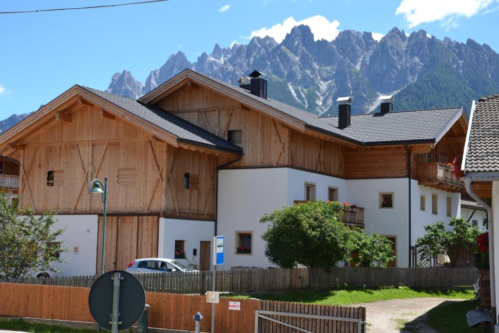 a house with a fence and mountains in the background at Mutznhof in Dobbiaco