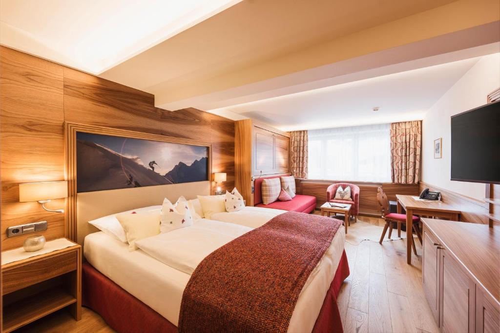 Gemütliches Zimmer im Hotel Arlberghaus mit rustikalen Holzmöbeln, komfortablem Doppelbett und Fenster mit Bergblick
