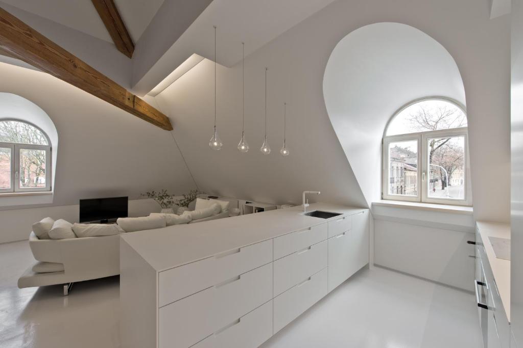 a kitchen with white cabinets and a couch and windows at City Entrance Apartment in Vilnius