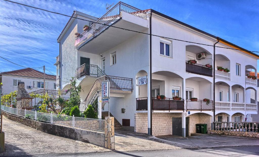 a large white building with balconies on a street at Apartments Milenka in Trogir