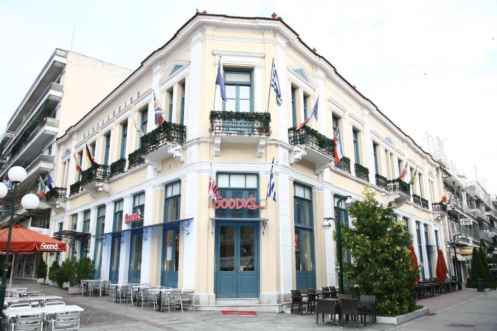 a large white building with tables and chairs on a street at Hotel Panellinion in Tríkala