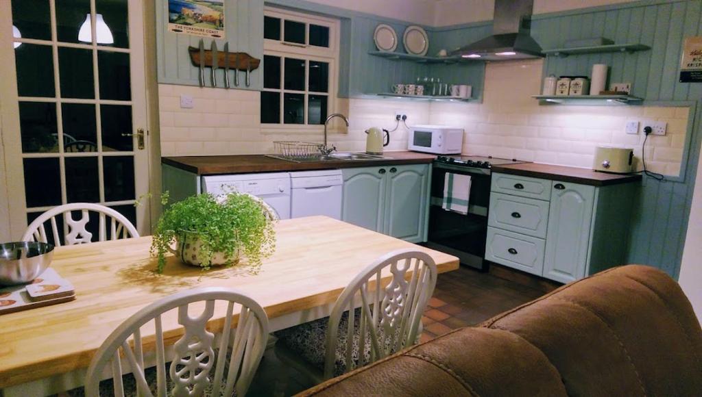 uma cozinha com uma mesa e um sofá em Milliner's Cottage em York