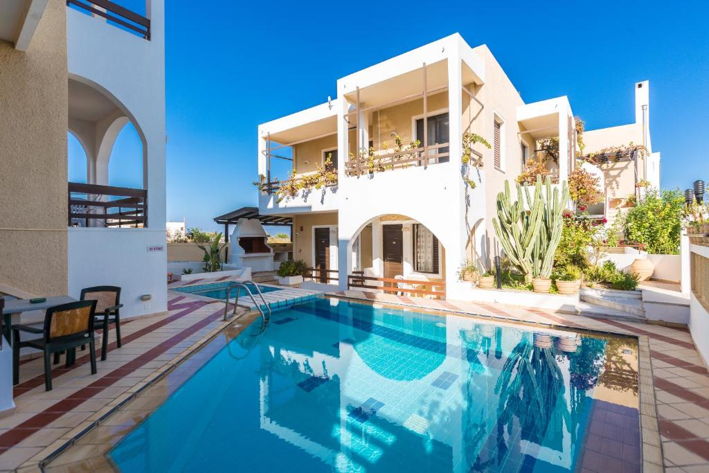 a villa with a swimming pool in front of a house at Rosebay Apartments in Sfakaki