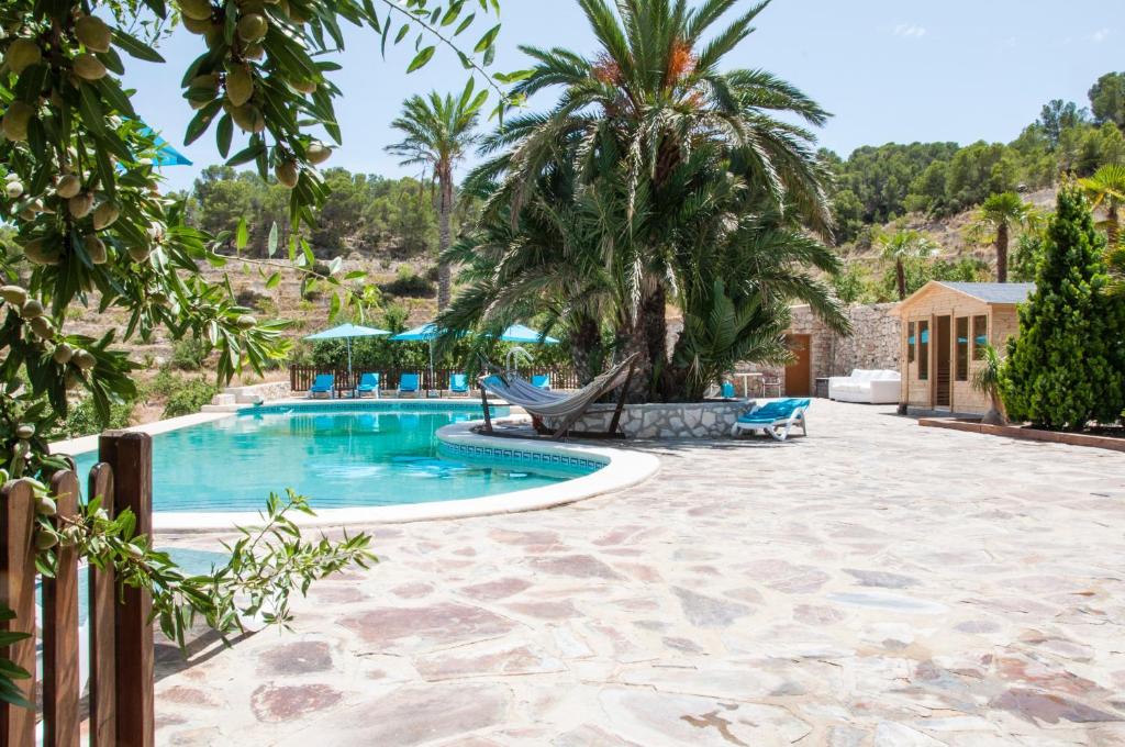uma piscina de resort com rede de descanso e palmeiras em Finca El Almendral em Relleu