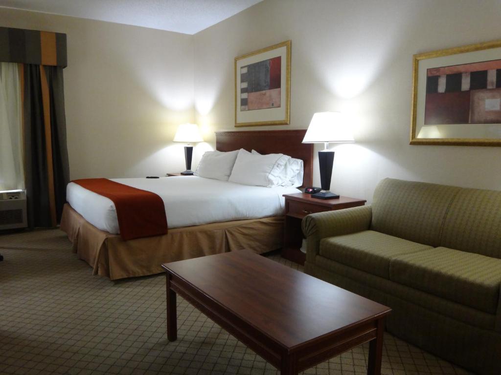 um quarto de hotel com uma cama e um sofá em Windsor Inn & Suites em Dodge City