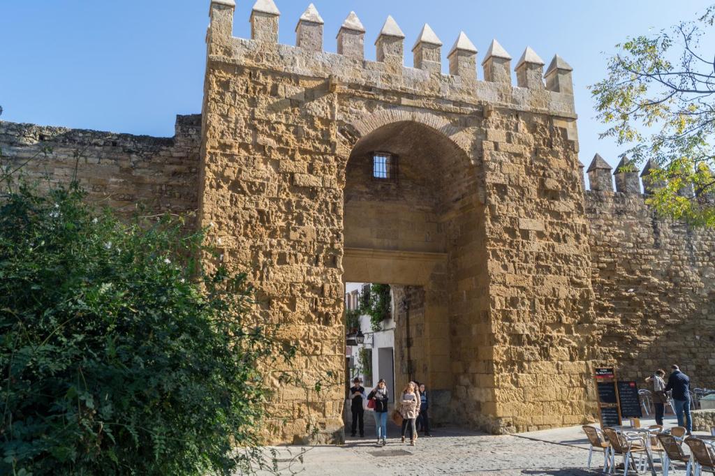 des personnes marchant à travers une arche d'un mur de briques dans l'établissement Casa Ruano, à Cordoue