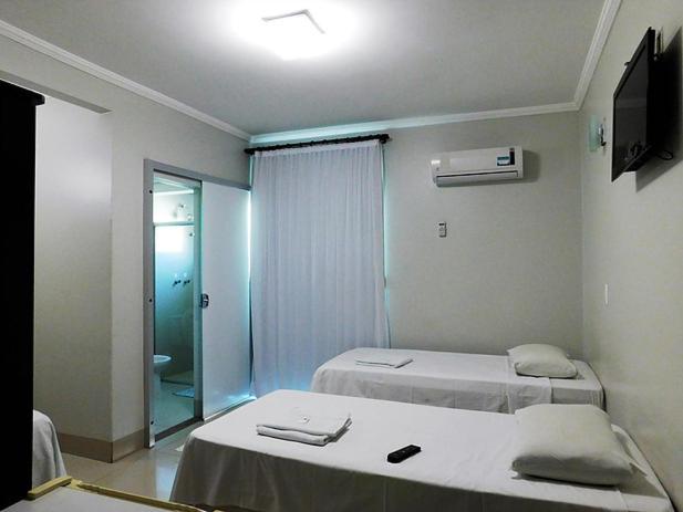 a hospital room with two beds and a television at Hotel Minas in Três Marias