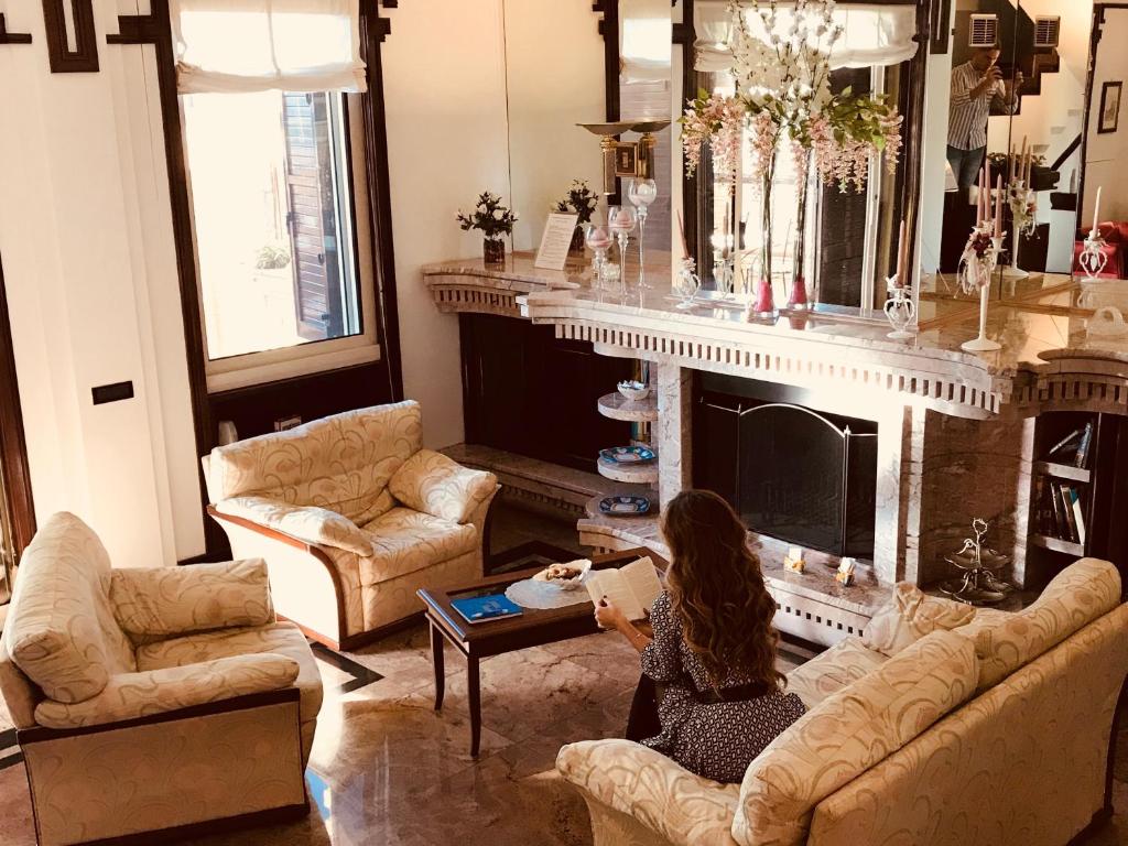 una donna seduta in un soggiorno con camino di BB La Maison Royale a Fiumicino