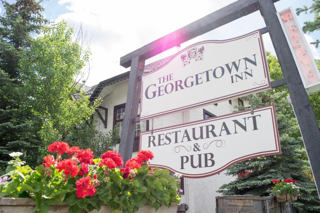 - un panneau indiquant l'auberge et le pub-restaurant avec des fleurs dans l'établissement The Georgetown Inn, à Canmore