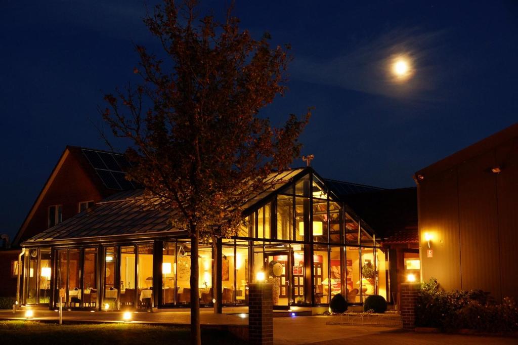 une maison en verre la nuit avec la lune dans le ciel dans l'établissement Acedo Land- und Sporthotel Levenhagen Greifswald, à Levenhagen