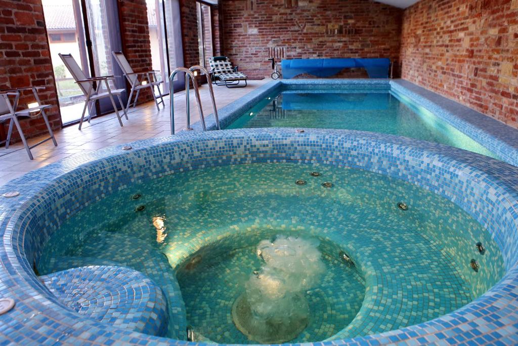 una gran piscina profunda en una habitación con una pared de ladrillo en Woodland Villa en Gyula