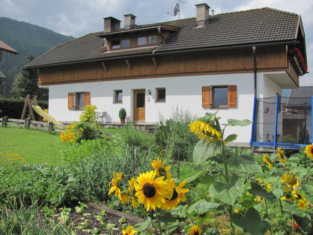 ein Haus mit einem Garten mit Sonnenblumen in der Unterkunft Appartements Hoferhof in Niederdorf