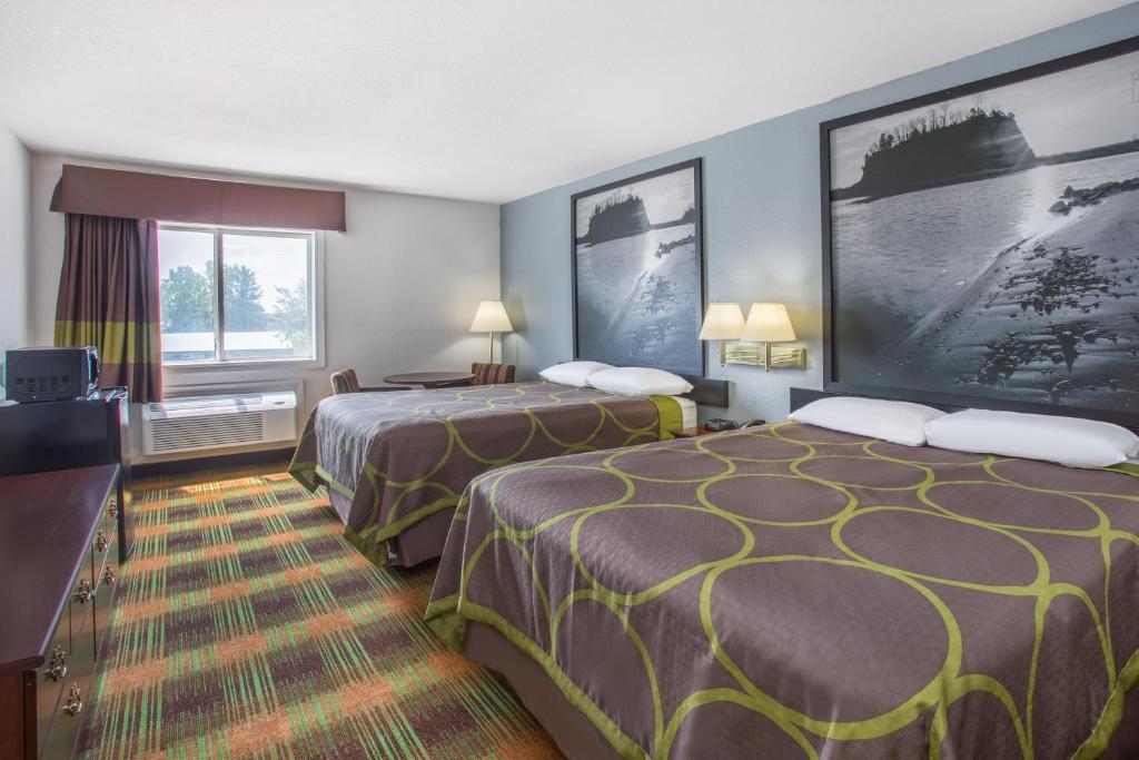 a hotel room with two beds and a television at Super 8 by Wyndham Sweet Springs in Sweet Springs