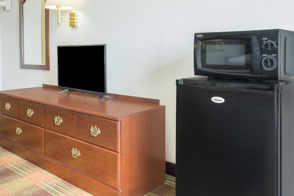 a tv sitting on top of a dresser next to a dresser with at Super 8 by Wyndham Sweet Springs in Sweet Springs