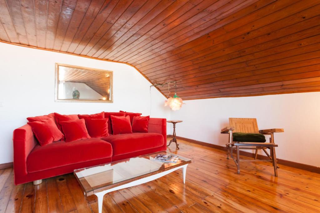 リスボンにあるBairrus Lisbon Apartments - Alfama IIIの木製天井のリビングルーム(赤いソファ付)