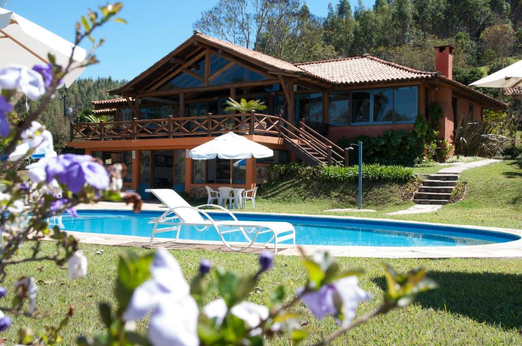 a house with a swimming pool in front of a house at Pousada Maria Manhã in Passa Quatro