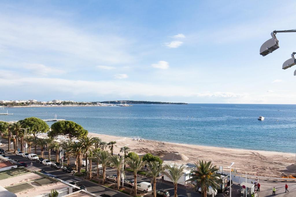 une vue sur une plage avec des palmiers et l'océan dans l'établissement Violet, bord de mer, à Cannes