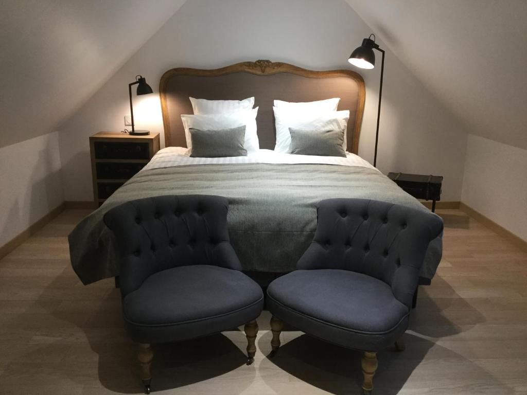a bedroom with a bed with a blue tufted bedspread and a chair at Auberge de Keranden in Landerneau