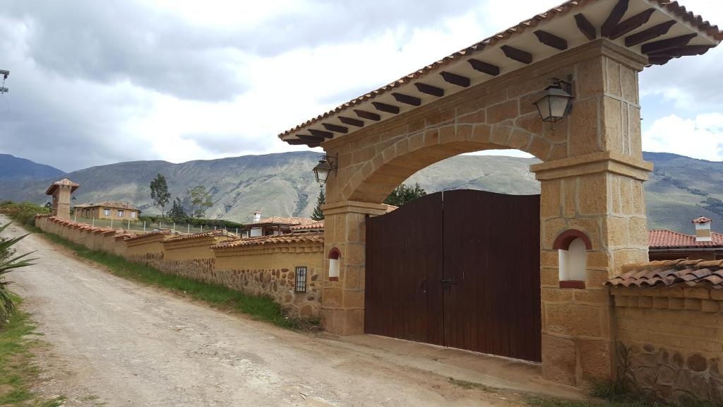 ein Tor in einer Steinmauer mit einer Schotterstraße in der Unterkunft Cabañas Sol y Luna in Villa de Leyva