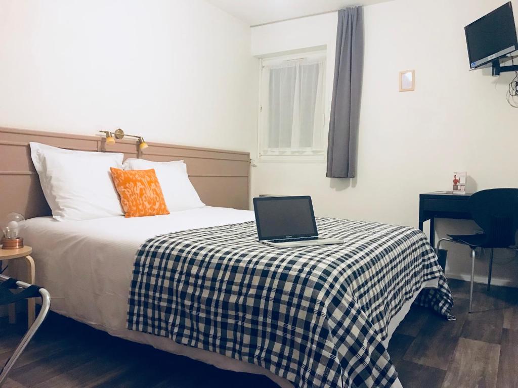 a bedroom with a bed with a laptop on it at Tourhôtel in Béthune