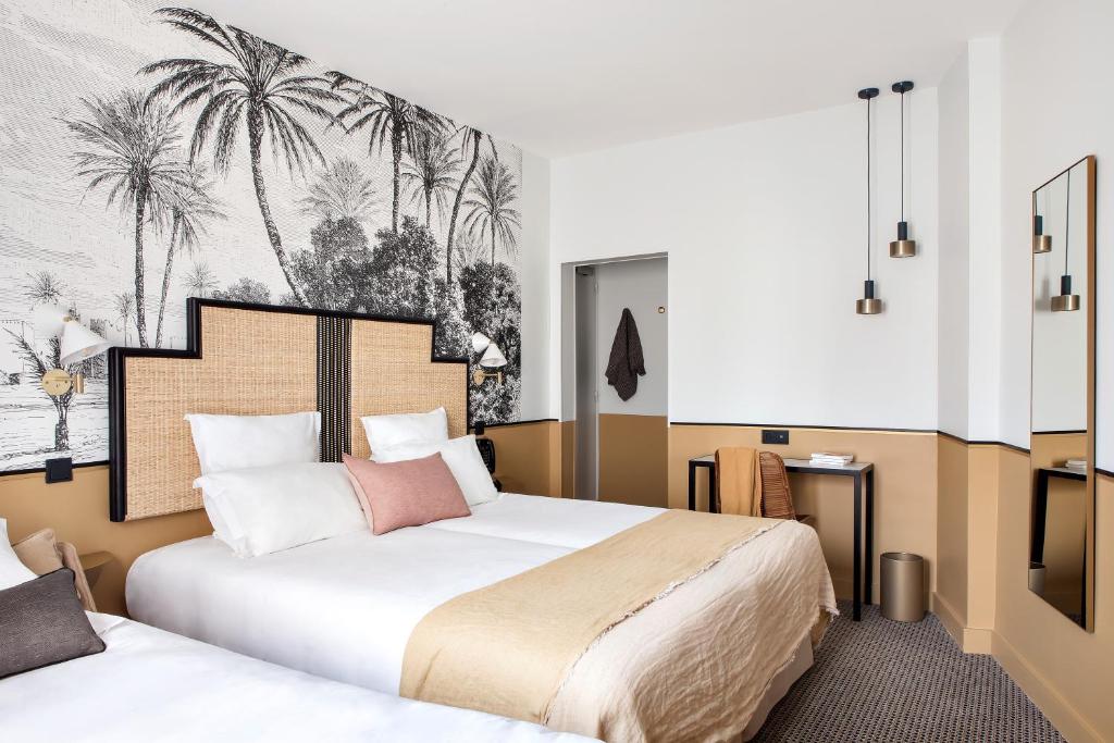 a hotel room with two beds and a mural of palm trees at Doisy Etoile in Paris