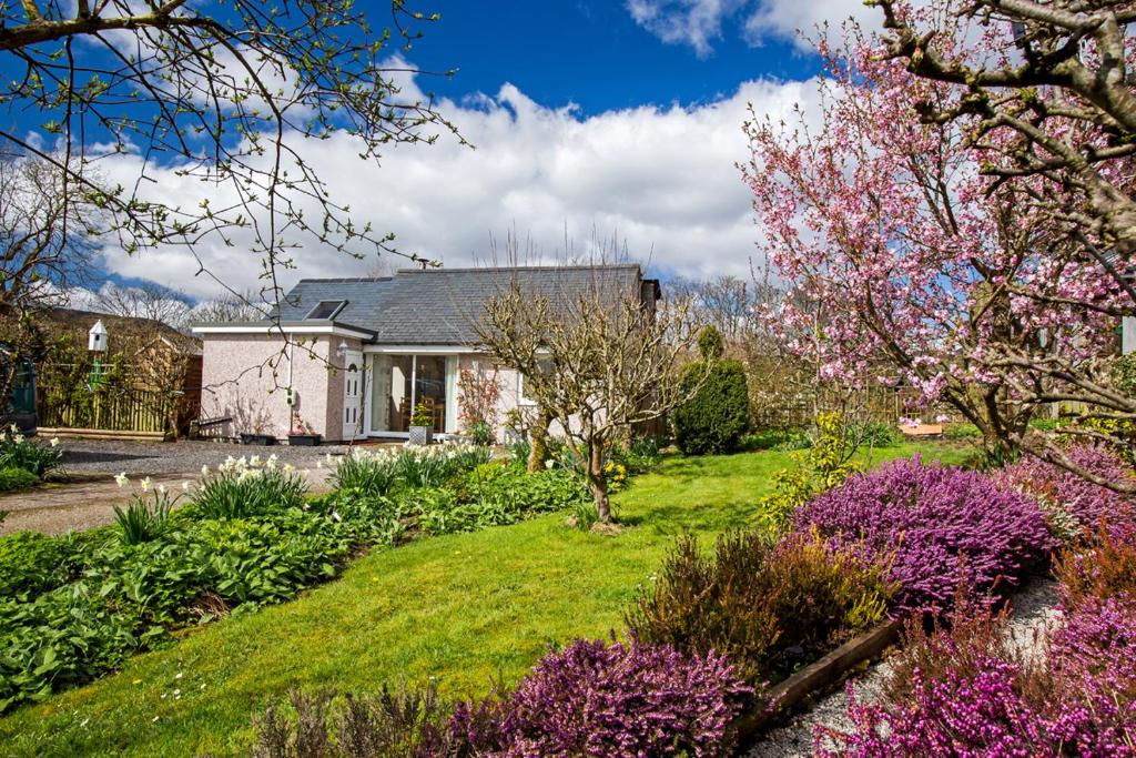 dom z ogrodem z kwiatami na dziedzińcu w obiekcie Ty'r Afon - River Cottage w mieście Bala
