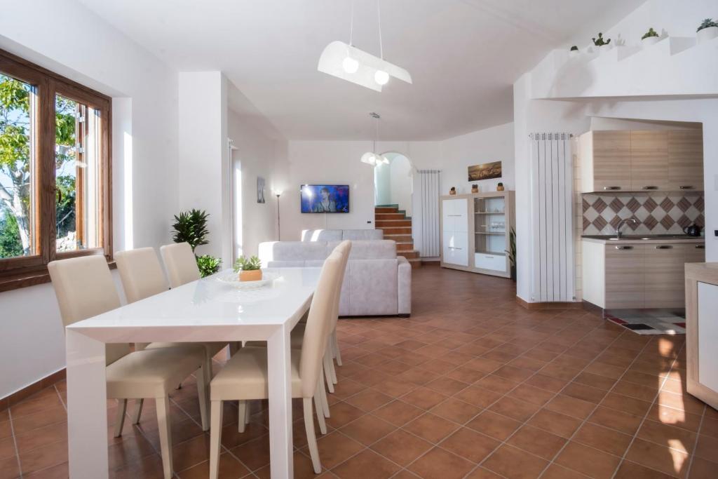 a dining room and living room with a white table and chairs at Villa d'aMare Capri View in Massa Lubrense
