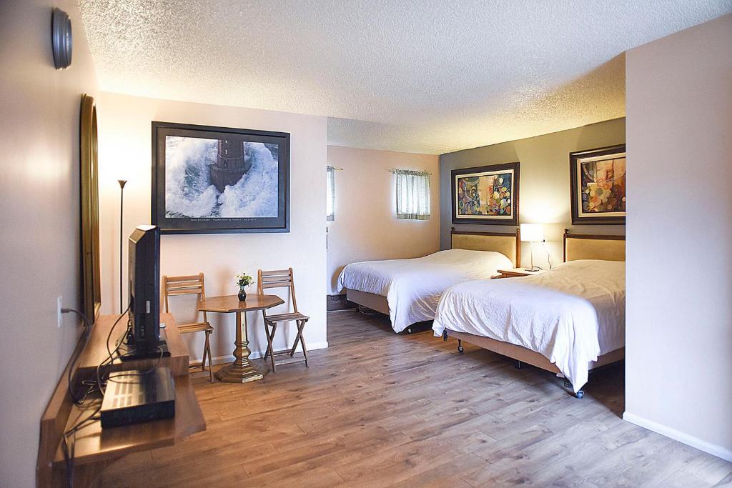 Habitación de hotel con 2 camas, mesa y TV. en H&H Motor Lodge, en Idaho Springs