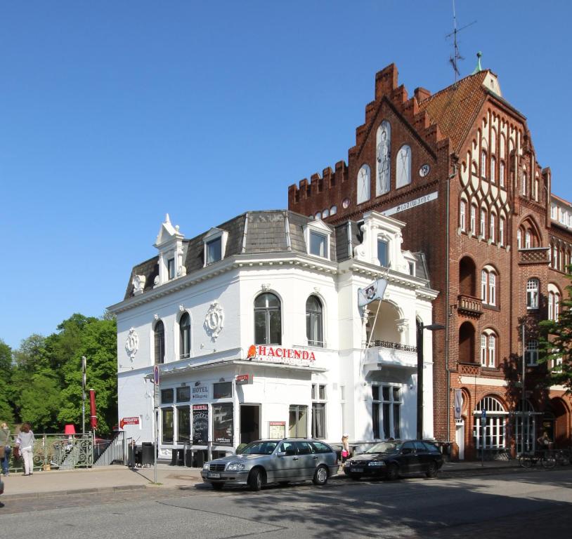 Biały budynek z samochodem zaparkowanym przed nim w obiekcie Hotel Excellent w Lubece