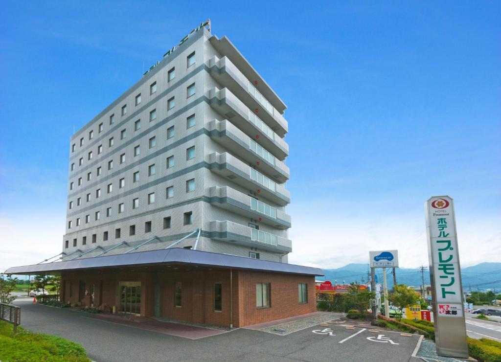 Un alto edificio bianco seduto sopra un edificio di Komagane Premont Hotel a Komagane