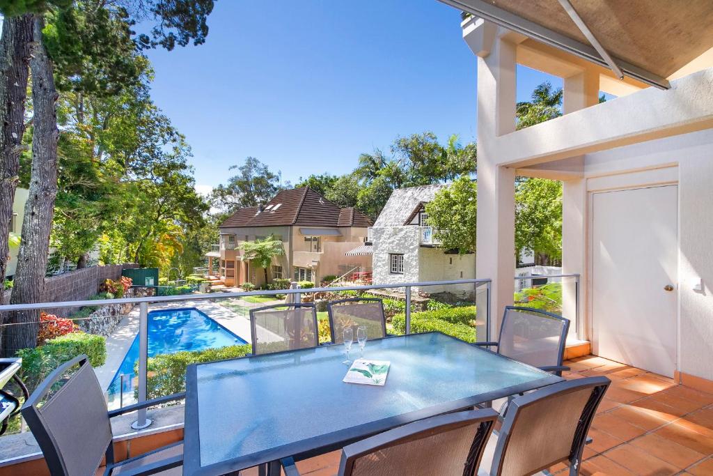 een patio met een blauwe tafel en stoelen en een zwembad bij Alderly Apartment 6, Little Cove in Noosa Heads