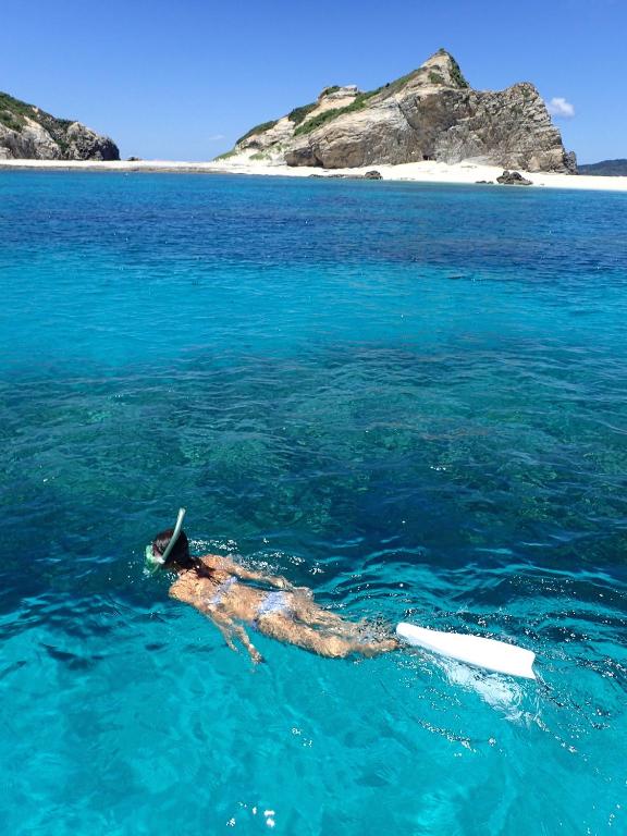 a person laying on a surfboard in the water at Kerama Terrace in Tokashiki