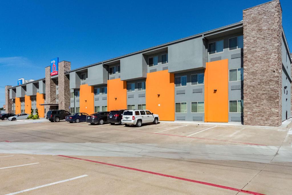 普萊諾的住宿－Studio 6-Plano, TX，停车场内有车辆停放的公寓大楼
