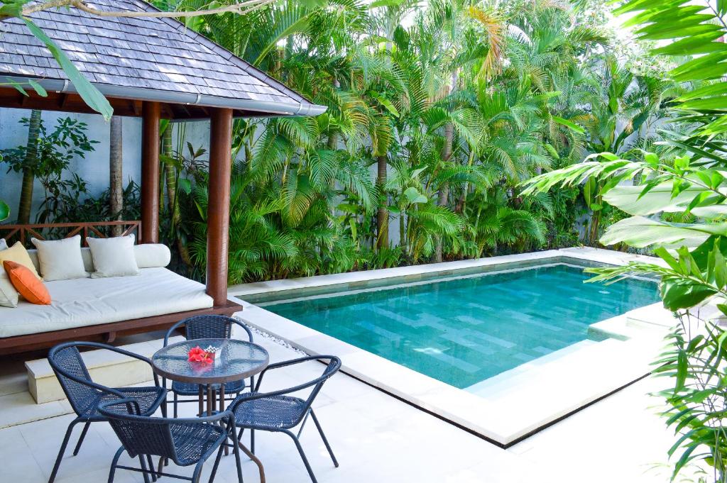 a patio with a pool and a table and chairs at Seminyak Villa Lumina in Seminyak
