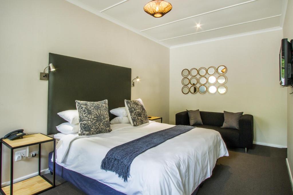 a bedroom with a large bed and a couch at Hlangana Lodge in Oudtshoorn