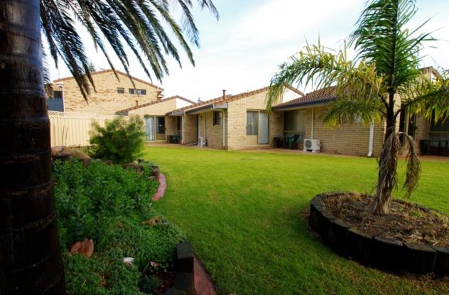 a yard with a house and a palm tree at Esperance Beachfront Resort in Esperance