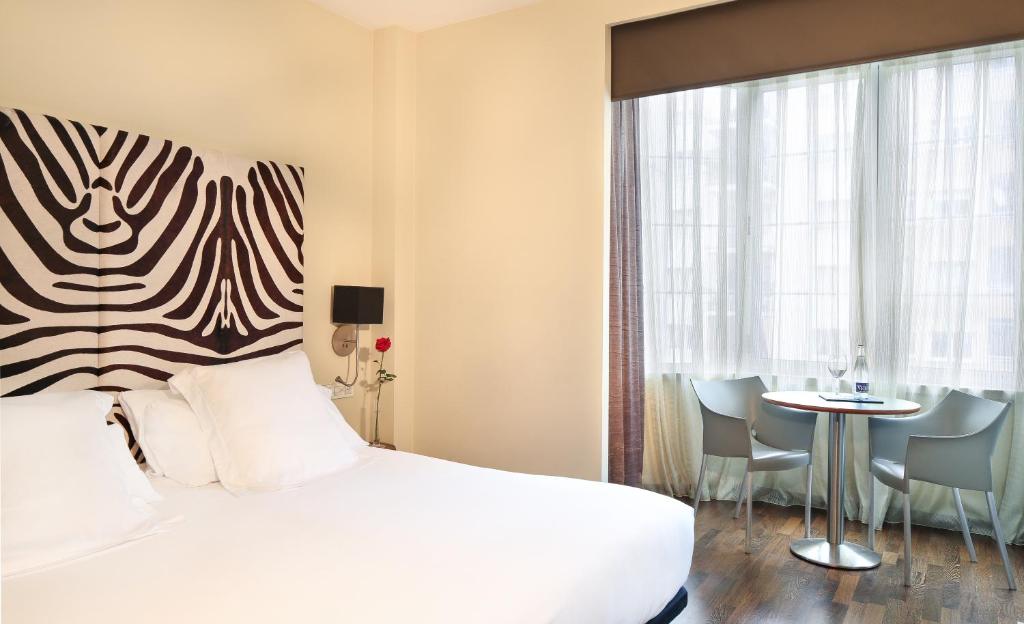 バルセロナにあるHotel Gran Derby Suites, a Small Luxury Hotel of the Worldのベッド、テーブル、椅子付