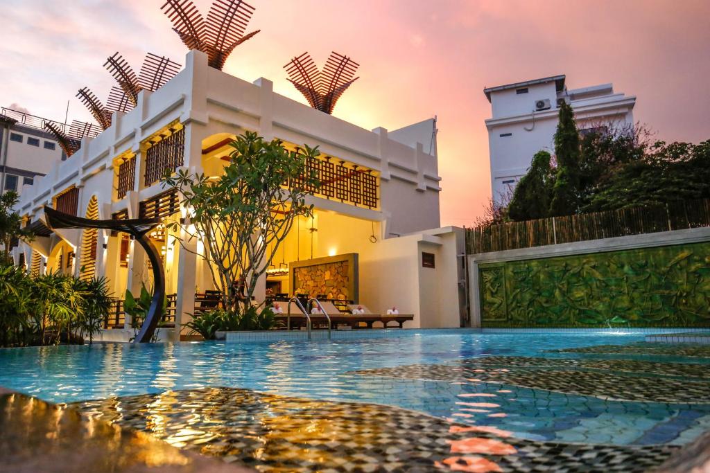 a villa with a swimming pool in front of a building at The Night Hotel in Siem Reap