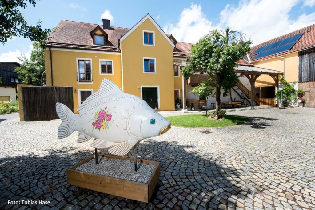 una estatua de un pez frente a una casa en Fischhof Beer en Mitterteich