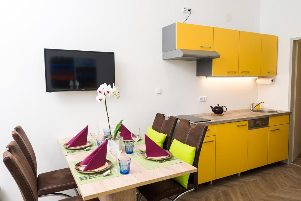 kuchnia ze stołem z krzesłami i żółtymi szafkami w obiekcie Apartments Villa Luna w Wiedniu