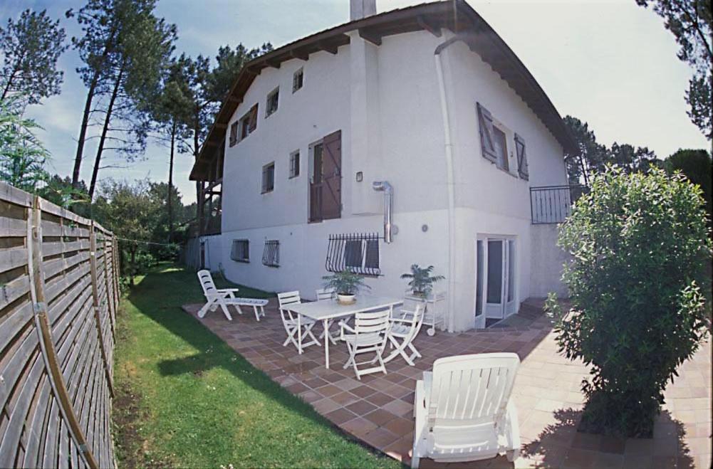 Casa blanca con mesa y sillas en el patio en L'Hernani, en Capbreton