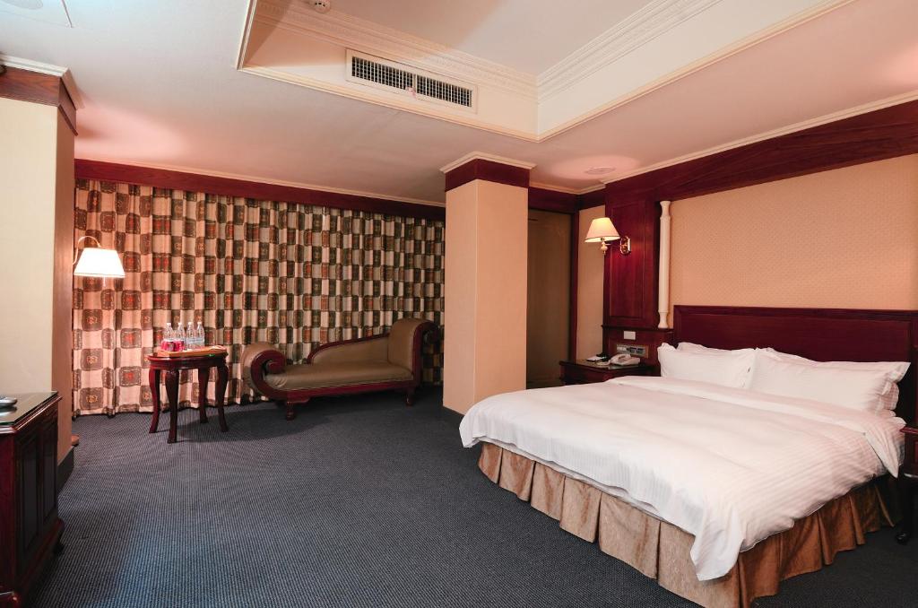 una habitación de hotel con una cama grande y una silla en Duke Business Hotel en Taoyuan